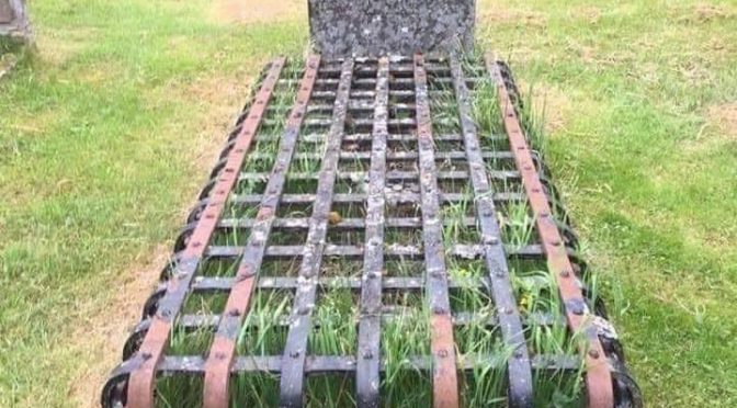 A grave, covered with a steel cage which is sunken into the ground.